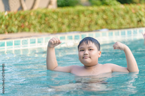 Obese fat boy show muscle in swimming pool