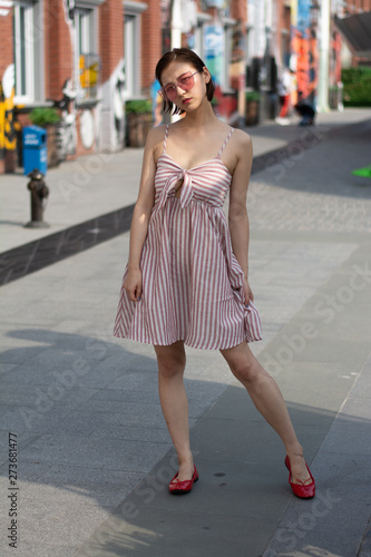 Asian Chinese model girl influencer street shot. Wearing pink dress and red shoes. Street Graffiti background.