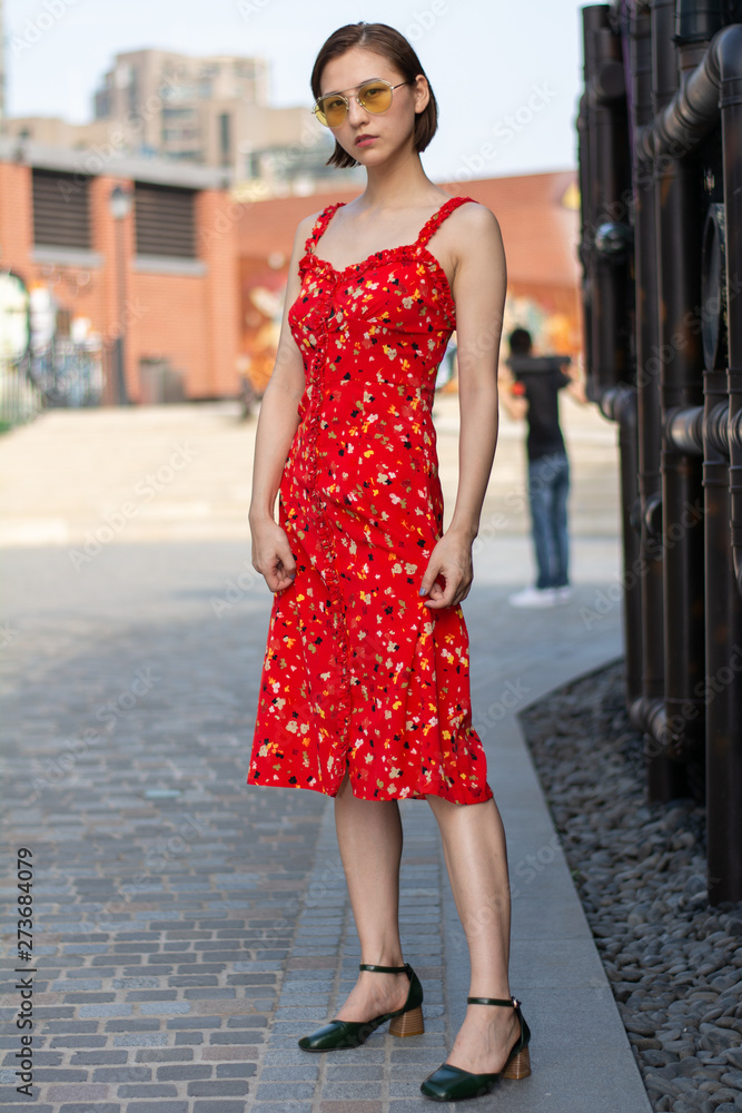 Asian Chinese model girl influencer street shot. Wearing red floral printed dress. Street view background. Asian Chinese model girl influencer street shot. Wearing red floral printed dress. Street view background.