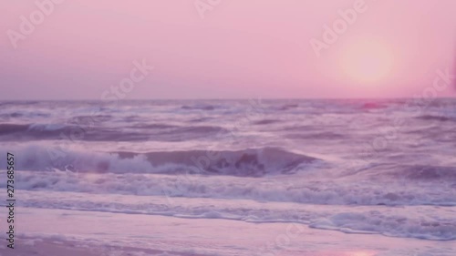surf of the waves, foam on the background of a pink dawn, the sun