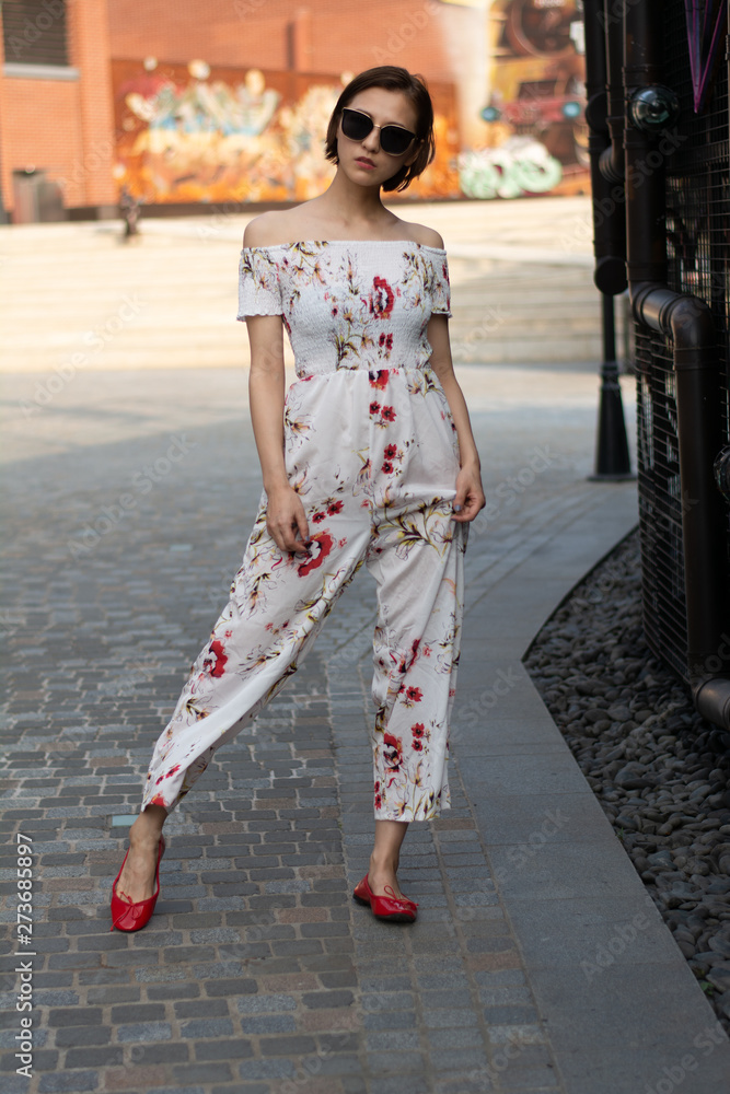Asian Chinese model girl influencer street shot. Wearing white printed floral patterned jumpsuit. Street view background. Asian Chinese model girl influencer street shot. Wearing white printed floral patterned jumpsuit. Street view background.