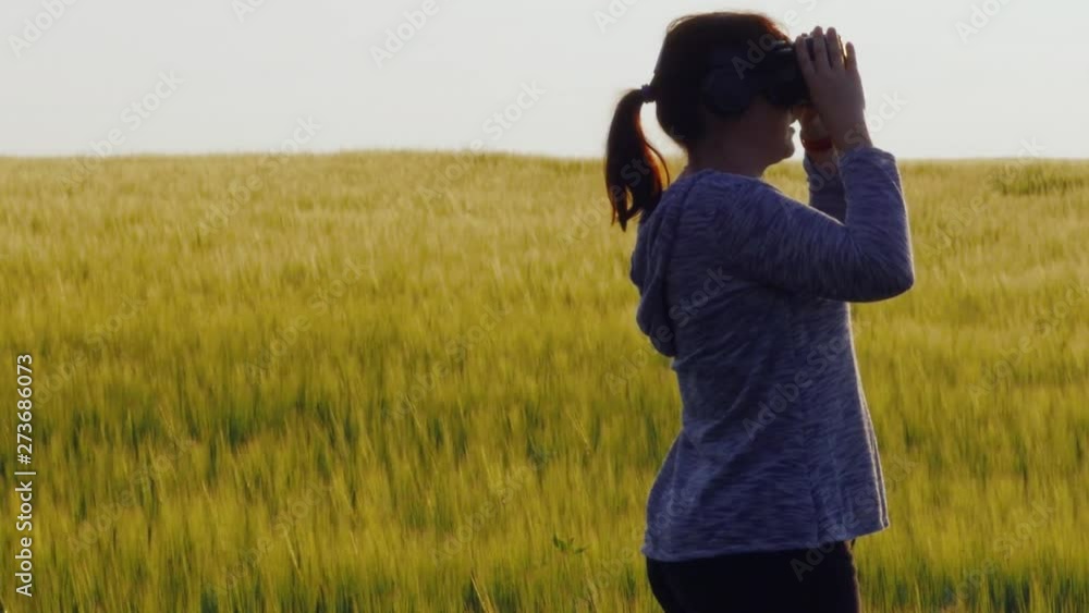 A beautiful girl uses virtual reality glasses against the sunset in a wheat field. slow motion A beautiful girl uses virtual reality glasses against the sunset in a wheat field. slow motion