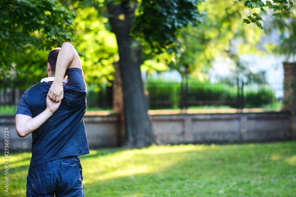 Sunset in park with trees and green grass. Handsome man do stretching exercises at autumn park. Sunset in park with trees and green grass. Handsome man do stretching exercises at autumn park.