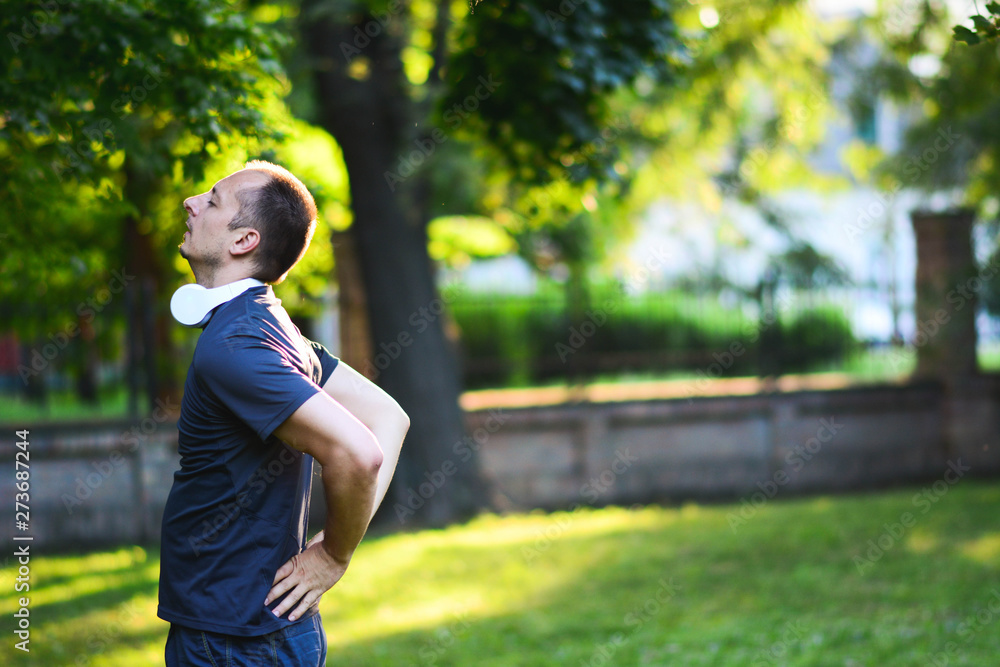 Sport injury, Man with back pain. Sunset in park with trees and green grass. Sport injury, Man with back pain. Sunset in park with trees and green grass.
