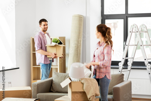 home, people, repair and real estate concept - smiling couple with big cardboard boxes and stuff moving to new place © Syda Productions