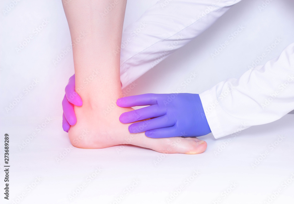 The doctor conducts a medical examination of the patient's ankle joint to detect arthritis and synovitis, trauma, luxation