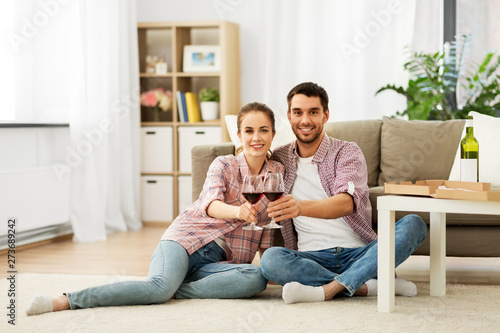 leisure, celebration and valentines day concept - happy couple drinking red wine at home