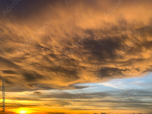 Dramatic sky with clouds on gold and red colour. Abstract of Storm cloudy is coming during Sunset over the sky. © chayakorn