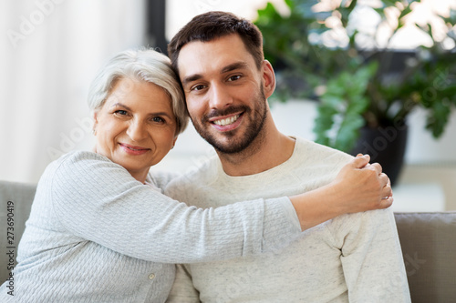 family, generation and people concept - happy smiling senior mother with adult son hugging at home photo