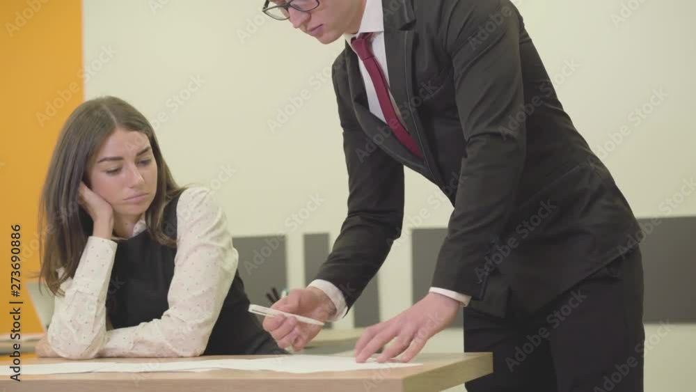 Angry young boss yelling at his secretary correcting her mistakes in documents. The girl is sad and scared. Conflict situation. Office life. The relationship of the boss and subordinate. Workplace. Angry young boss yelling at his secretary correcting her mistakes in documents. The girl is sad and scared. Conflict situation. Office life. The relationship of the boss and subordinate. Workplace.