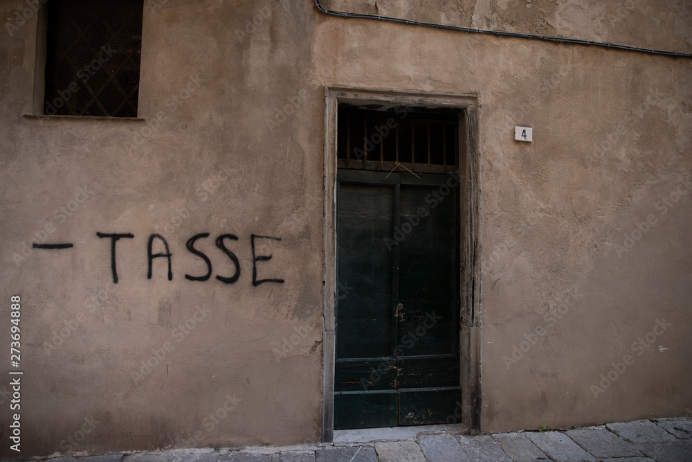 Fototapeta premium writing on a wall asking for less taxes. Albenga, Italy