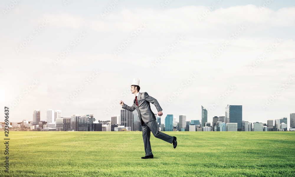 King businessman in elegant suit running on green grass and modern cityscape at background King businessman in elegant suit running on green grass and modern cityscape at background