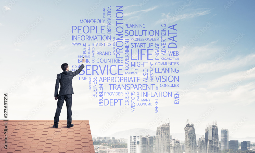 Young businessman standing on house roof and writing leadership Young businessman standing on house roof and writing leadership