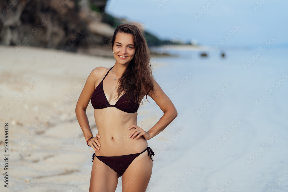 Happy girl with perfect body in black swimwear posing on white sand beach Happy girl with perfect body in black swimwear posing on white sand beach