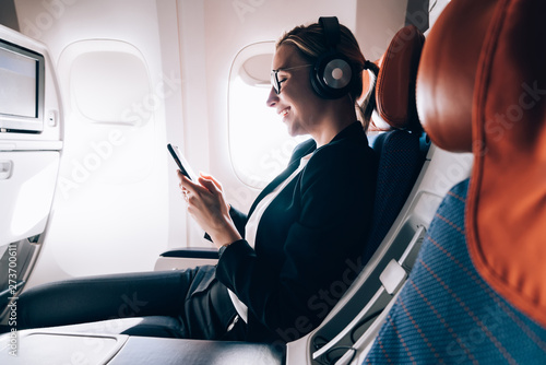 Quadro em tela Cheerful female passenger in headphones for noise cancellation watching online m