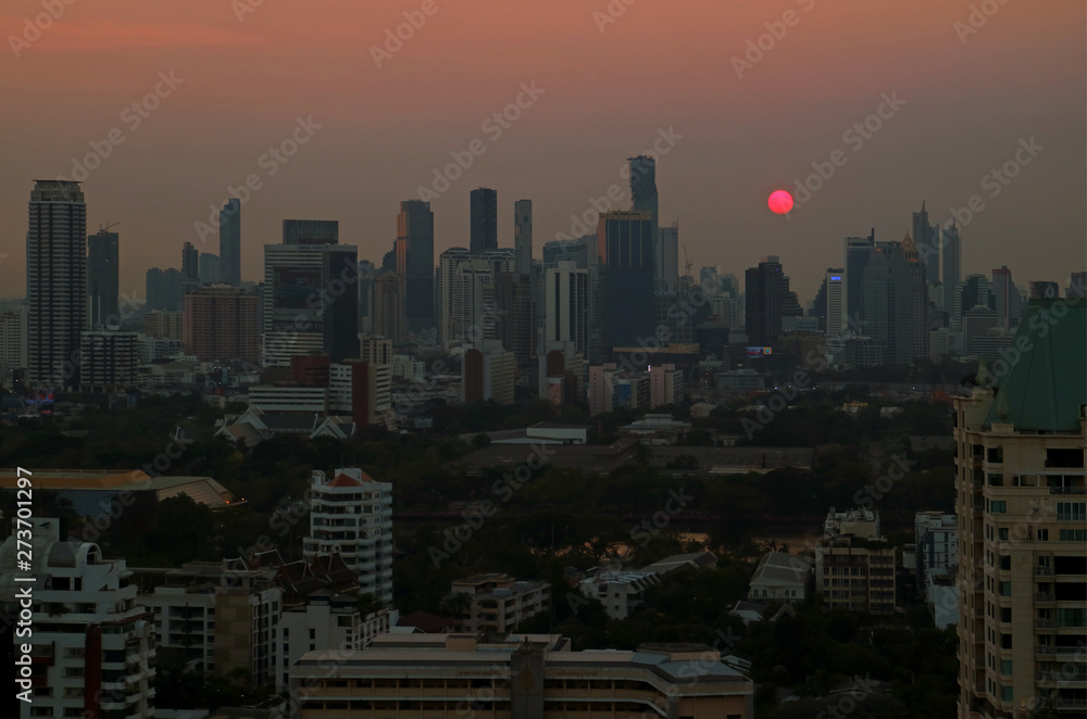 Panoramic view of the sun setting over skyscrapers in Bangkok downtown, Thailand