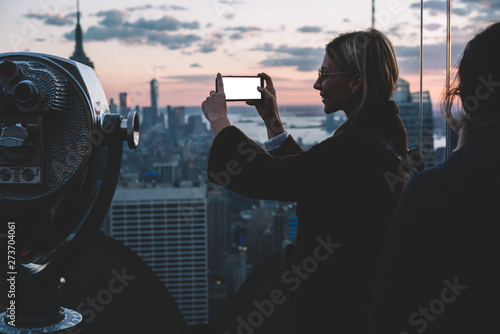 Female tourist preparing her smartphone camera for make photo of scenery New York view from open Observation deck. Hipster girl photographing on mobile phone city landmark during USA vacation holidays