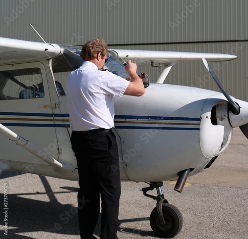 Pilot in uniform doing pre-flight inspection on airplane before take off - safety first concept