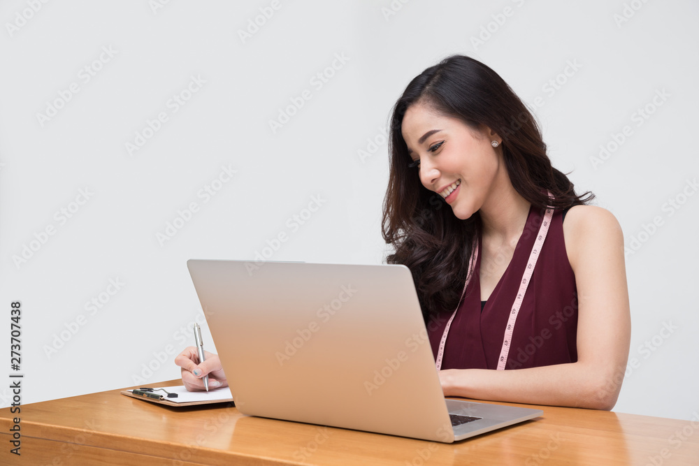 Woman fashion designer clothes in red dress with measuring tape and laptop computer isolated over white background, Asian female stylish model Woman fashion designer clothes in red dress with measuring tape and laptop computer isolated over white background, Asian female stylish model