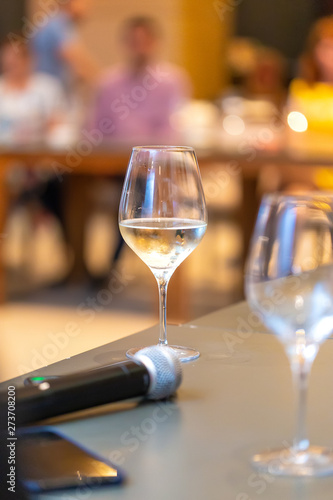 White wine glasses near the microphone on the table in a conference room