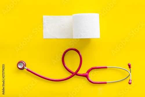 Disease of colon concept with toilet paper roll and stethoscope on yellow background top view