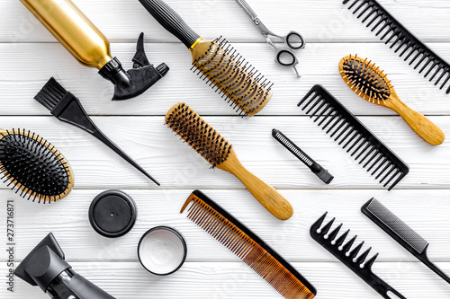professional accessories of hairdresser with combs and sciccors on work desk wooden white background top view pattern