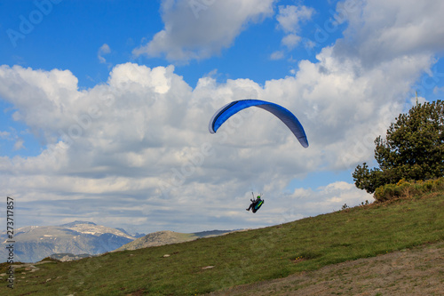 Paragliding flying through the green meadows