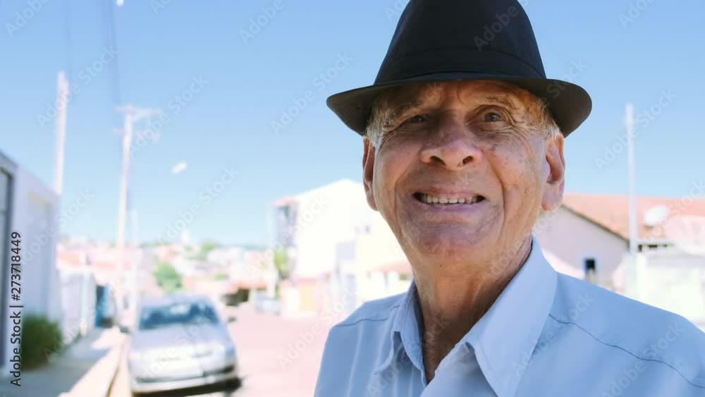 Old man Brazilian. Very old man portrait on the background of small city in sunny summer weather. Old gentleman in hat and blue shirt. Old man Brazilian. Very old man portrait on the background of small city in sunny summer weather. Old gentleman in hat and blue shirt.
