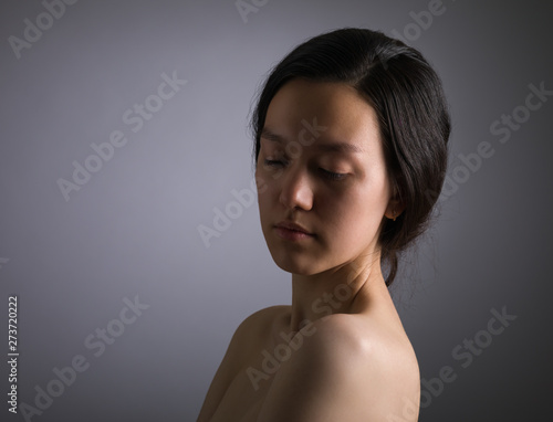 Portrait of sad young Asian woman on dark background.