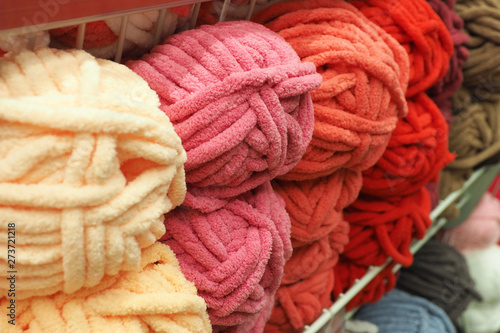 Many multicolored balls of plush yarn in metal mesh trays..