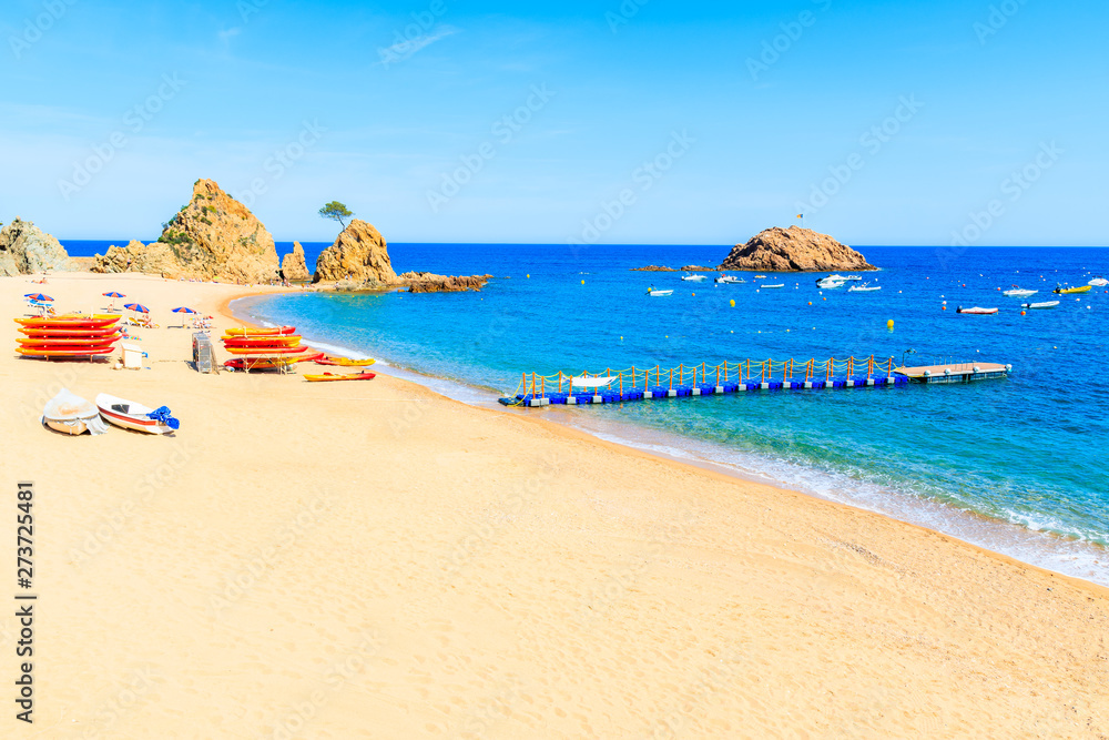 Azure blue water on idyllic beach with fishing boats in Tossa de Mar town, Costa Brava, Spain
