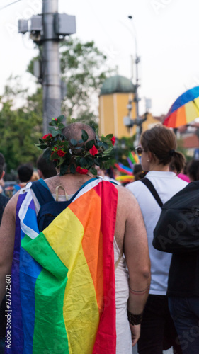Sofia / Bulgaria - 10 June 2019: Fat guy with Rainbow Flag in the back and Crown of flowers supporting Sofia Pride walking in the street in the march