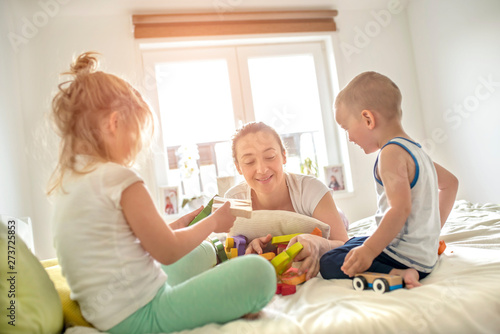 Happy mother playing educational toys with kids at home