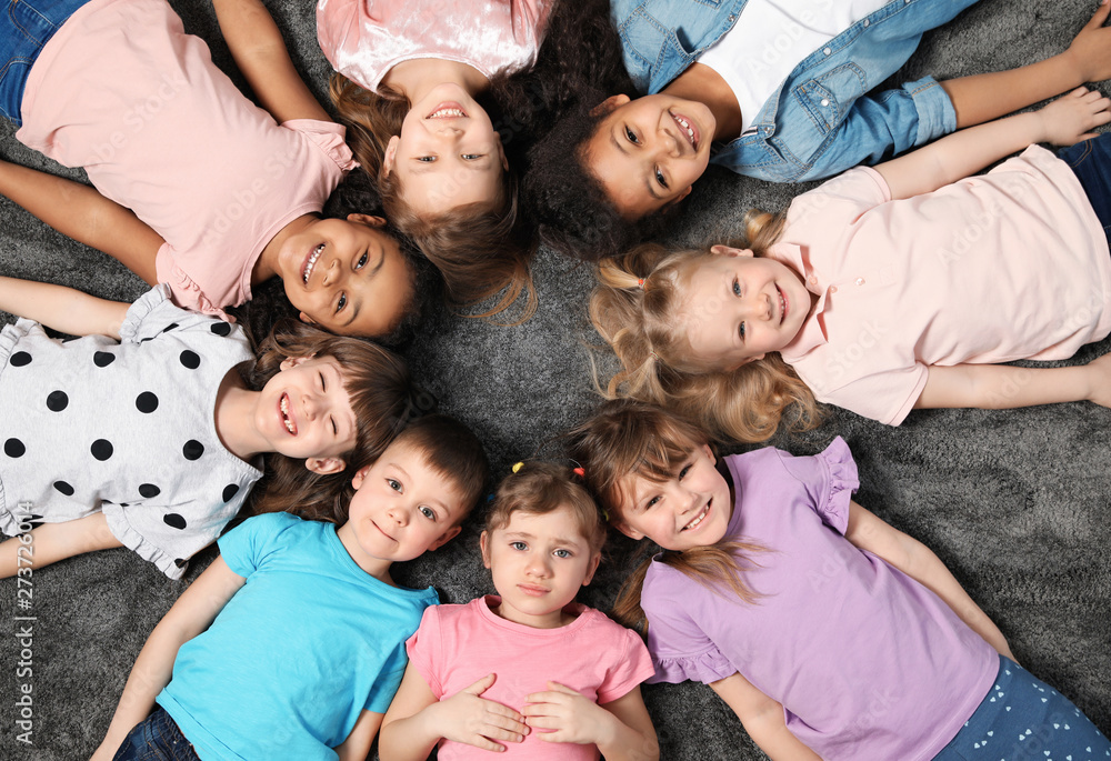 Adorable little children lying on floor together indoors, top view. Kindergarten playtime activities