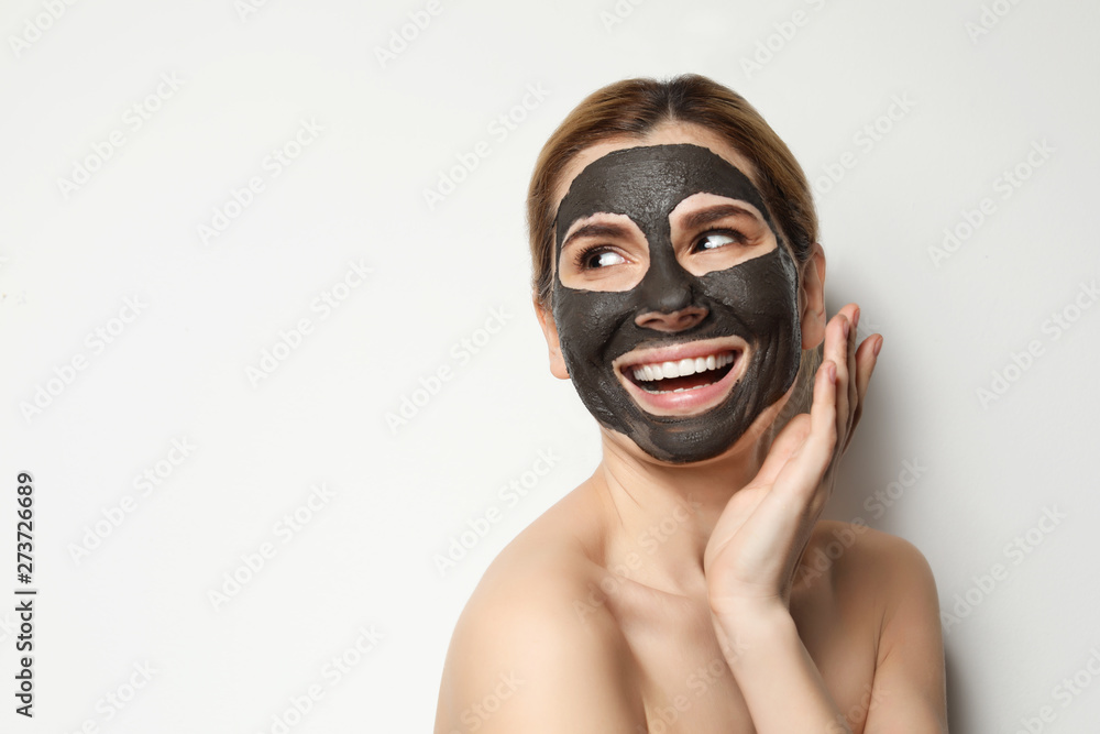 Beautiful woman with black mask on face against light background. Space for text Beautiful woman with black mask on face against light background. Space for text