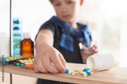 Foto Little child taking pills from shelf at home, closeup