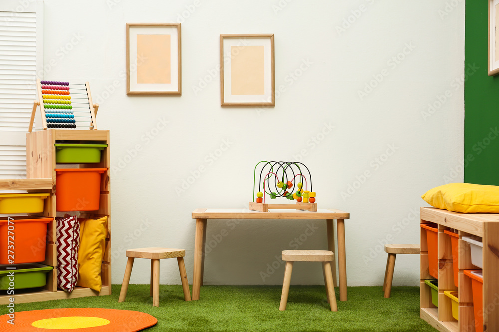 Stylish playroom interior with table and stools