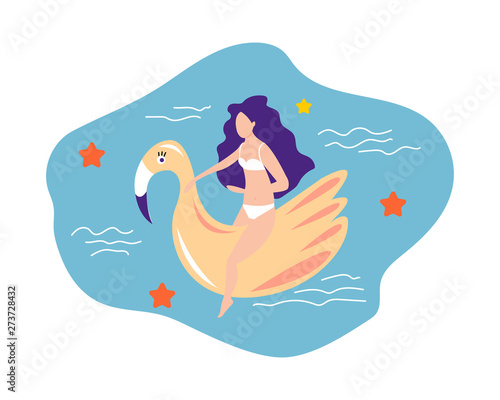 Girl in a swimsuit sits on an inflatable flamingo in the pool. Summer concept.