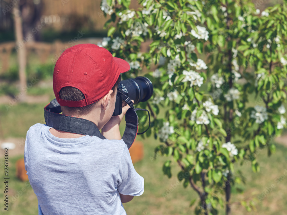 Fototapeta premium Obtaining new skills. Cute European boy is taking shoots in the garden.