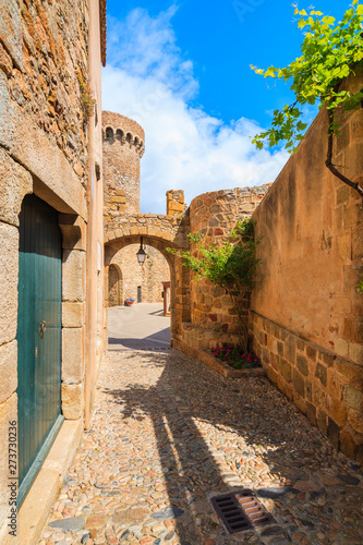 Narrow street and castle gate in historic old town of Tossa de Mar, Costa Brava, Spain