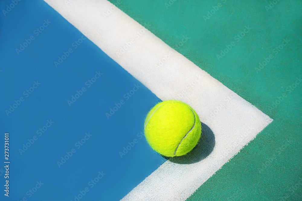 Summer sport concept with tennis ball on white line on hard tennis court. Flat lay, top view, copy space, close up. Blue,green and yellow.