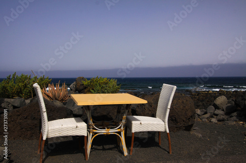 Isolated two white chairs and table on black lava sand beach with ocean and waves background - El Golfo, Lanzarote © Ralf
