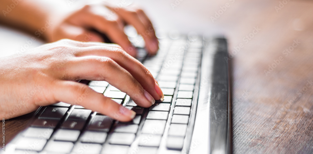 Woman working at home office hand on keyboard close up on wooden table background Woman working at home office hand on keyboard close up on wooden table background