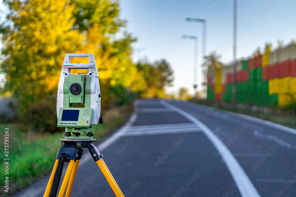 Surveyor engineer with equipment (theodolite or total positioning station) on the construction site of the road or building with construction colorful background Surveyor engineer with equipment (theodolite or total positioning station) on the construction site of the road or building with construction colorful background