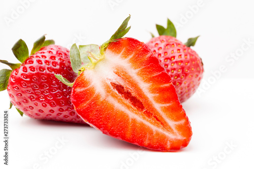 Red cut strawberry close up isolated on white. A fresh and bright red strawberry macro studio shot. Great for healthy eating concepts