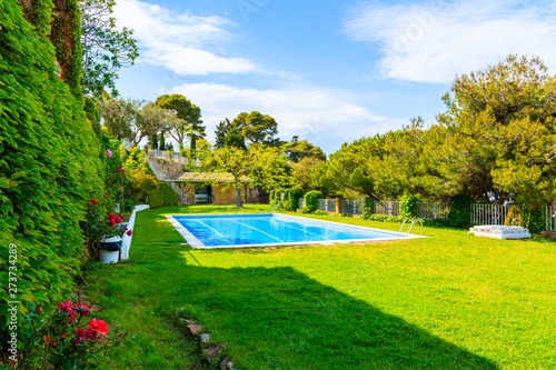 TOSSA DE MAR, SPAIN - JUN 3, 2019: Swimming pool in garden of luxury house in Tossa de Mar town, Costa Brava, Spain.