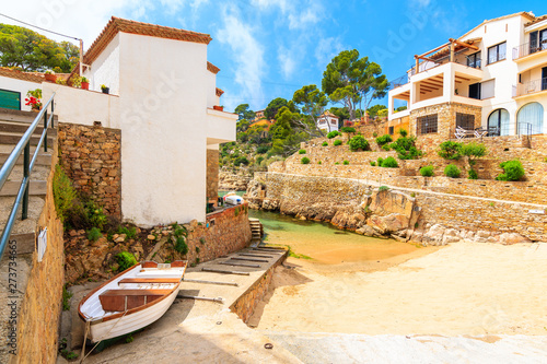 View of beach with fishing boat and holiday apartments in Fornells village, Costa Brava, Spain