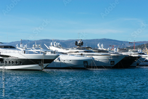 White expensive yachts on a background of mountains on a sunny day. Yacht parking in Cannes, France. Mediterranean Sea.