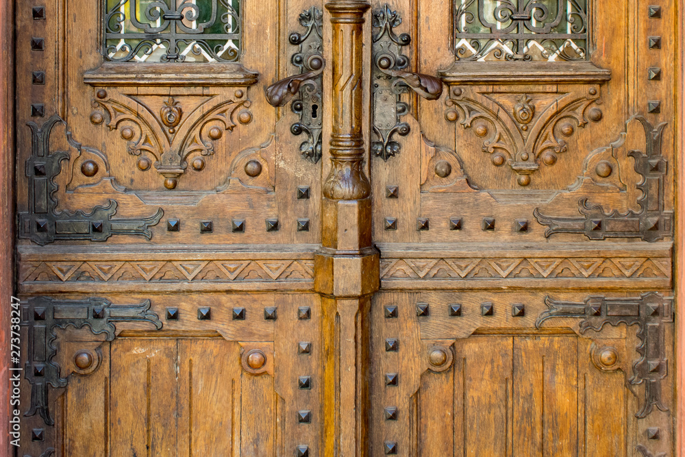 Steampunk ancient wooden door with handmade decoration, carving, metal handles and windows.
