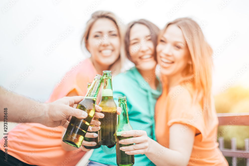 Green beer bottles clinking - roof top summer party - happy friends toasting and celebrating, focus on the hands Green beer bottles clinking - roof top summer party - happy friends toasting and celebrating, focus on the hands